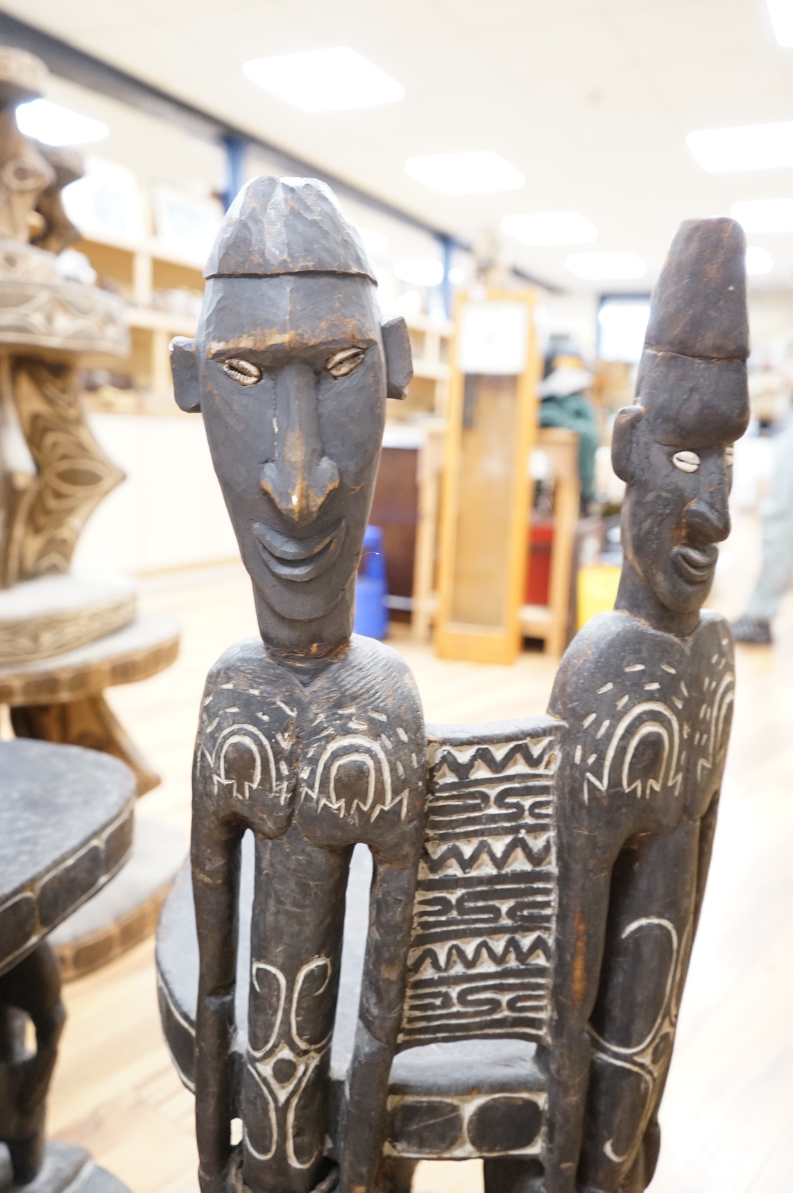 Papua New Guinea Sepik River, a near pair of ‘ceremonial’ figural chairs, each carved from a single section of a tree trunk with integral male and female backs and an castor figure front support with cowrie shell eyes. H